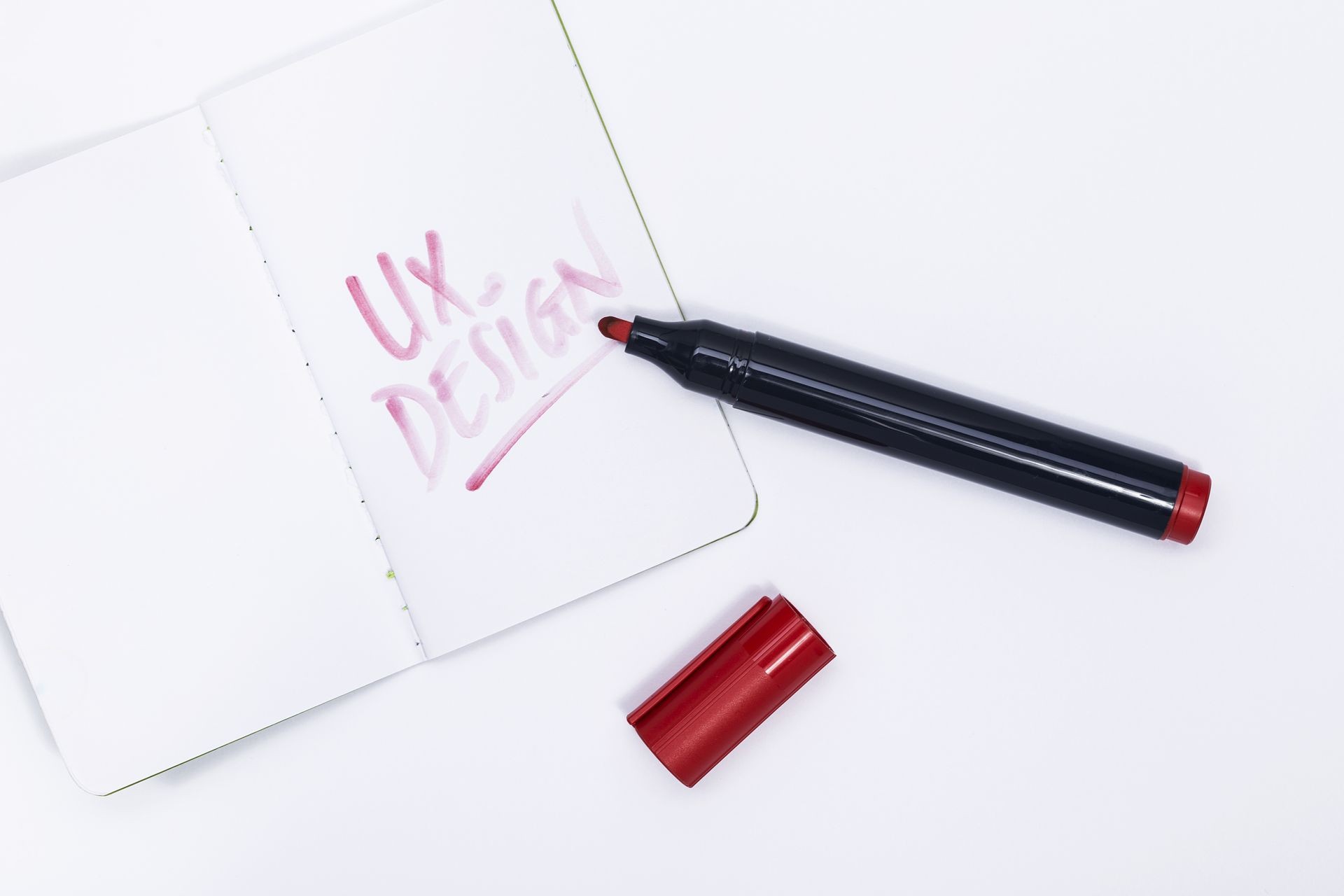 Red marker pen writing UX design on notepad